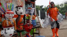 Petugas Unit Penanganan Sampah (UPS) Badan Air (BA) Dinas Lingkungan Hidup DKI Jakarta Kecamatan Jatinegara membuat ondel-ondel mini dari galon air minum bekas di Jakarta, Selasa (25/6/2024). (Liputan6.com/Herman Zakharia)