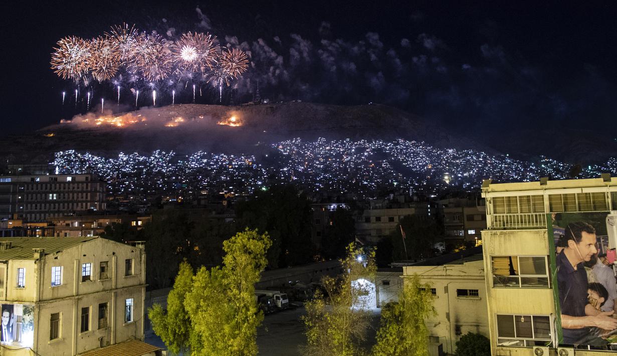 Kembang api meledak di atas Gunung Qasioun saat para pendukung merayakan kembali terpilihnya Presiden Suriah Bashar Assad di Damaskus, Kamis (27/5/2021). Bashar al-Assad terpilih kembali untuk masa jabatan keempat sebagai presiden Suriah yang dilanda perang. (AP Photo/Hassan Ammar)