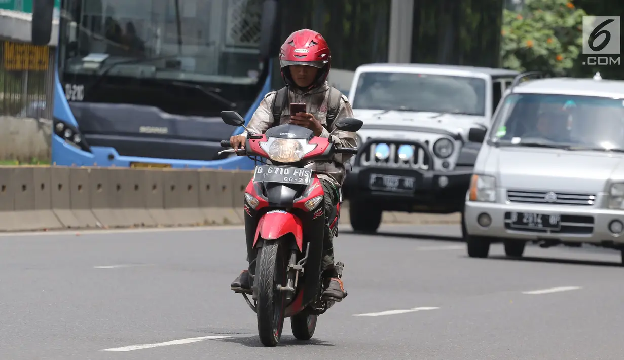 Warga mengoperasikan telepon seluler sambil mengendarai sepeda motor di Jalan Gatot Subroto, Jakarta, Kamis (8/3). Pengemudi yang membaca pesan teks pada telepon genggam akan memiliki risiko kecelakaan 23 kali lebih tinggi. (Liputan6.com/Arya Manggala)