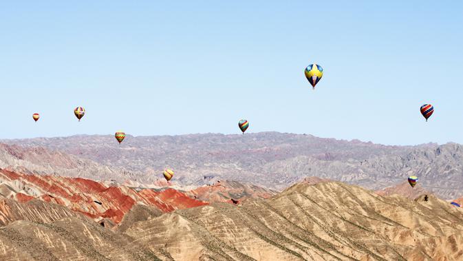Sejumlah balon udara terlihat di langit Taman Geologi Nasional Danxia di Zhangye, Provinsi Gansu, China barat laut, pada 26 Juli 2020. Sebuah festival balon udara internasional dibuka di Zhangye pada Minggu (26/7). Total 100 balon udara akan ditampilkan dalam festival tersebut. (Xinhua/Cheng Lin)