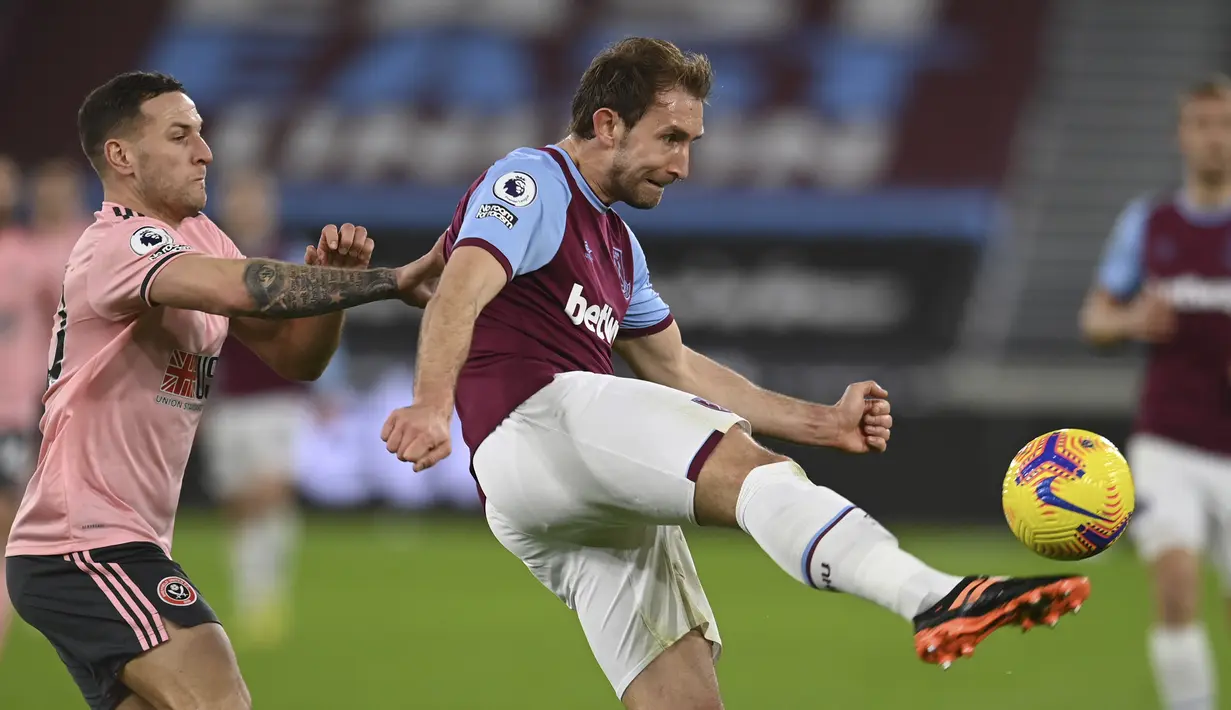 Bek West Ham United, Craig Dawson (kanan) menguasai bola dibayangi striker Sheffield United, Billy Sharp dalam laga lanjutan Liga Inggris 2020/21 pekan ke-24 di London Stadium, London, Senin (15/2/2021). West Ham menang 3-0 atas Sheffield United. (AP/Glyn Kirk/Pool)