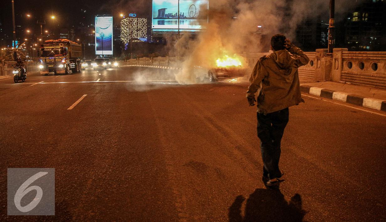 Pemilik mobil terdiam melihat mobilnya terbakar di jalan layang Latuharhari, Jakarta, Kamis (18/9/2015). Diduga kebakaran akibat konsleting listrik yang terjadi dibagian depan kap mobil. (Liputan6.com/Faizal Fanani)