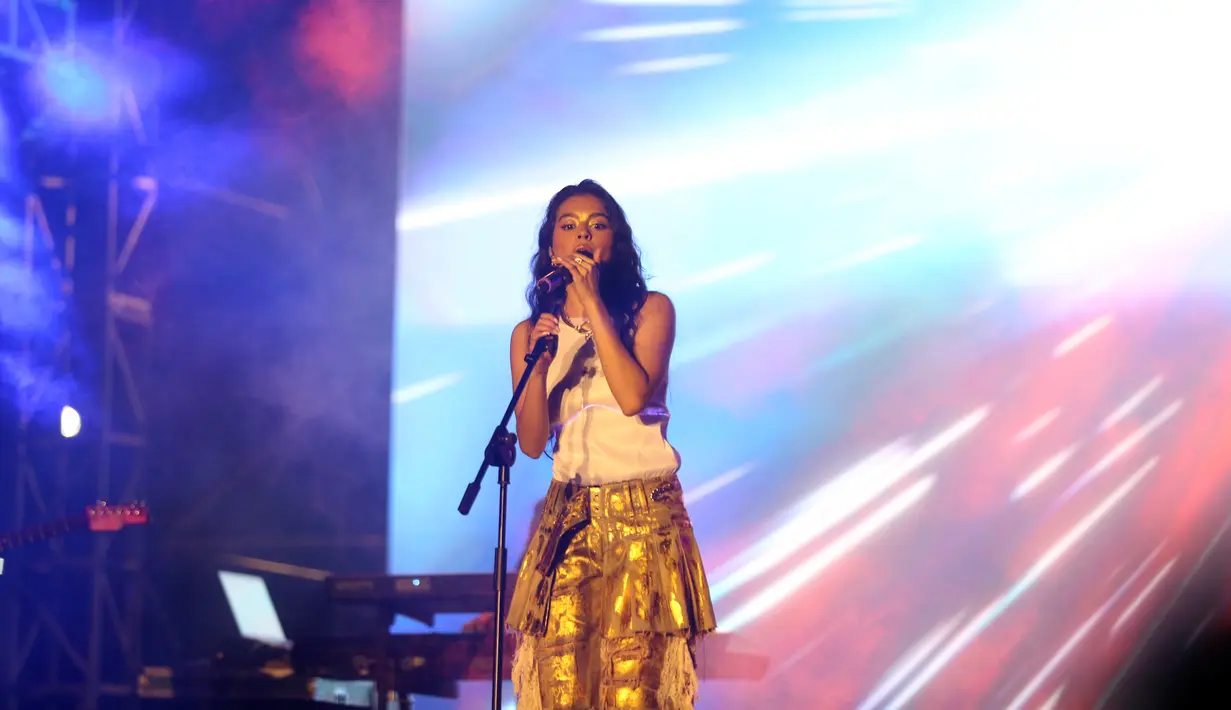 Tak hanya dengan musik, Eva juga mencuri perhatian dengan busana yang bersinar dalam gelap. Busana glow in the dark menciptakan aura Eva yang memesona dan energik di atas panggung. (Liputan6.com/Johan Tallo)