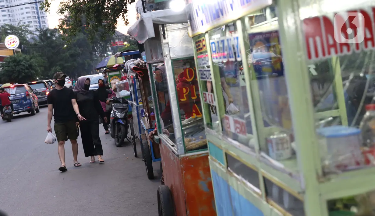 Warga melintasi deretan penjual makanan berbuka puasa di kawasan Bendungan Hilir, Jakarta, Sabtu (25/4/2020). Meski ditengah pandemi virus Covid-19, masyarakat masih antusias berburu penganan berbuka puasa dengan tetap menerapkan pola jaga jarak dan memakai masker. (Liputan6.com/Helmi Fithriansyah)