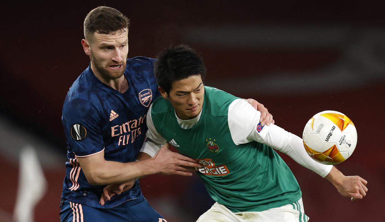 Striker Rapid Wien, Koya Kitagawa (kanan), menguasai bola dibawah tekanan bek Arsenal, Shkodran Mustafi, dalam laga lanjutan Liga Europa 2020/21 Grup B di Emirates Stadium, Kamis (3/12/2020) waktu setempat. Rapid Wien kalah 1-4 dari Arsenal. (AFP/Adrian Dennis)
