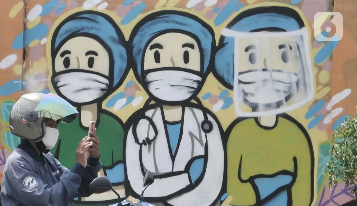 Pengendara melintas di depan mural dukungan untuk tim medis Covid-19 di kawasan Sunter, Jakarta, Rabu (27/5/2020). Mural tersebut sebagai bentuk dukungan untuk tim medis penanganan Covid-19 sekaligus mengingatkan masyarakat agar taat mengikuti aturan PSBB. (merdeka.com/Iqbal S. Nugroho)