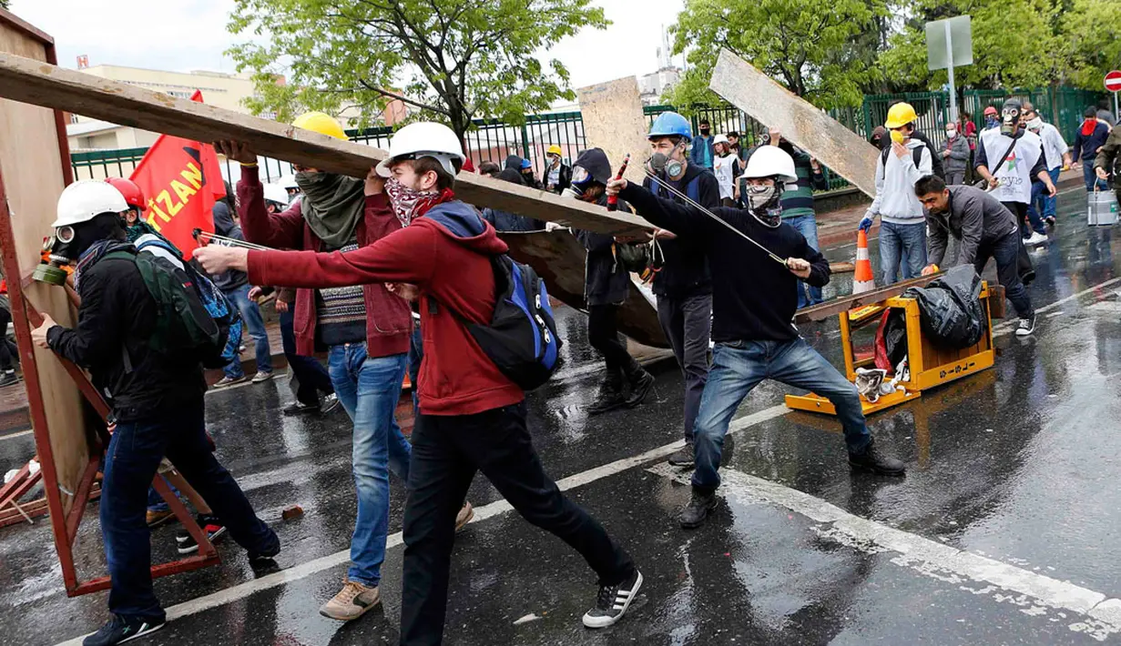 Dengan menggunakan ketapel, salah satu pengunjuk rasa menembaki polisi yang berjaga saat berlangsungnya peringatan Hari Buruh Sedunia di Istanbul, Turki (1/5/2014). (REUTERS/Umit Bektas)