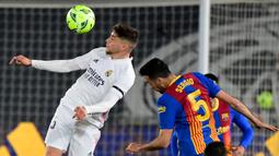 Gelandang Real Madrid, Federico Valverde (kiri) berduel udara dengan gelandang Barcelona, Sergio Busquets dalam laga lanjutan Liga Spanyol 2020/2021 pekan ke-30 di Alfredo di Stefano Stadium, Madrid, Sabtu (10/4/2021). Real Madrid menang 2-1 atas Barcelona. (AFP/Javier Soriano)