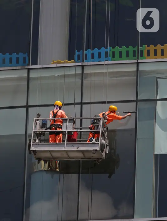 Pekerja membersihkan kaca gedung bertingkat di Jakarta, Kamis (2/4/2020). Keluarnya Peraturan Pemerintah (PP) Nomor 82 Tahun 2019 yang resmi berlaku pada 2 Desember 2019 diharapkan dapat meningkatkan jumlah perusahaan dan pekerja peserta skema BP Jamsostek. (Liputan6.com/Herman Zakharia)