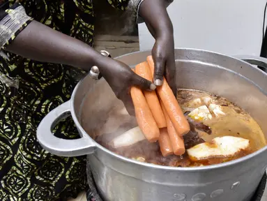 Koki Senegal Thiane Ngom menyiapkan "thiebou dieune" tradisional di rumahnya di Dakar pada 15 Desember 2021. Badan kebudayaan PBB (UNESCO) menambahkan hidangan nasional Senegal, sepiring nasi dengan ikan yang disebut 'thiebou dieune', ke dalam daftar warisan budayanya. (SEYLLOU/AFP)