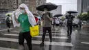 <p>Para komuter berjalan melintasi penyeberangan selama jam sibuk pagi hari pada hari hujan di Beijing, Rabu (29/6/2022). Pemerintah China mengurangi masa karantina wajib untuk pelancong yang merupakan pelonggaran pertama yang diterapkan negara itu kepada turis sejak Covid-19 merebak. (AP Photo/Mark Schiefelbein)</p>