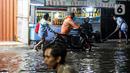 Pengendara sepeda motor mendorong kendaraannya saat melewati banjir di Jalan Ciracas Raya, Jakarta, Jumat (12/8/2022). Hujan lebat yang terjadi sore tadi membuat Jalan Ciracas Raya tergenang air dan kendaraan terjebak banjir. (Liputan6.com/Faizal Fanani)