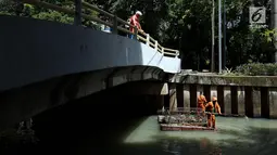 Turis asing melihat petugas kebersihan membersihkan kali Cideng, Jakarta, Senin (4/12). Membersihkan kali tersebut dilakukan rutin dikarenakan musim hujan dan mengantisipasi banjir yang kemungkinan bisa terjadi. (Liputan6.com/JohanTallo)