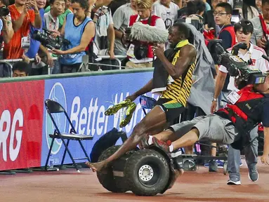 Usian Bolt terjatuh setelah ditabrak juru kamera yang menggunakan Segway saat merayakan kemenangan di nomor lari 200m Kejuaraan Dunia Atletik 2015 di Stadion Nasional, Beijing, Tiongkok. (27/8/2015). (Reuters)