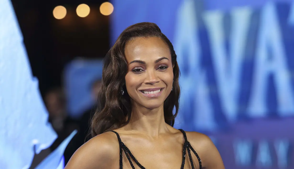 Zoe Saldana berpose sambil tersenyum saat menghadiri pemutaran perdana  film 'Avatar: The Way of Water' di London, Selasa, 6 Desember 2022. Aktris berusia 44 tahun itu memamerkan pinggangnya yang ramping dengan busana bermotif kupu-kupu biru yang ia kenakan. (Photo by Vianney Le Caer/Invision/AP)