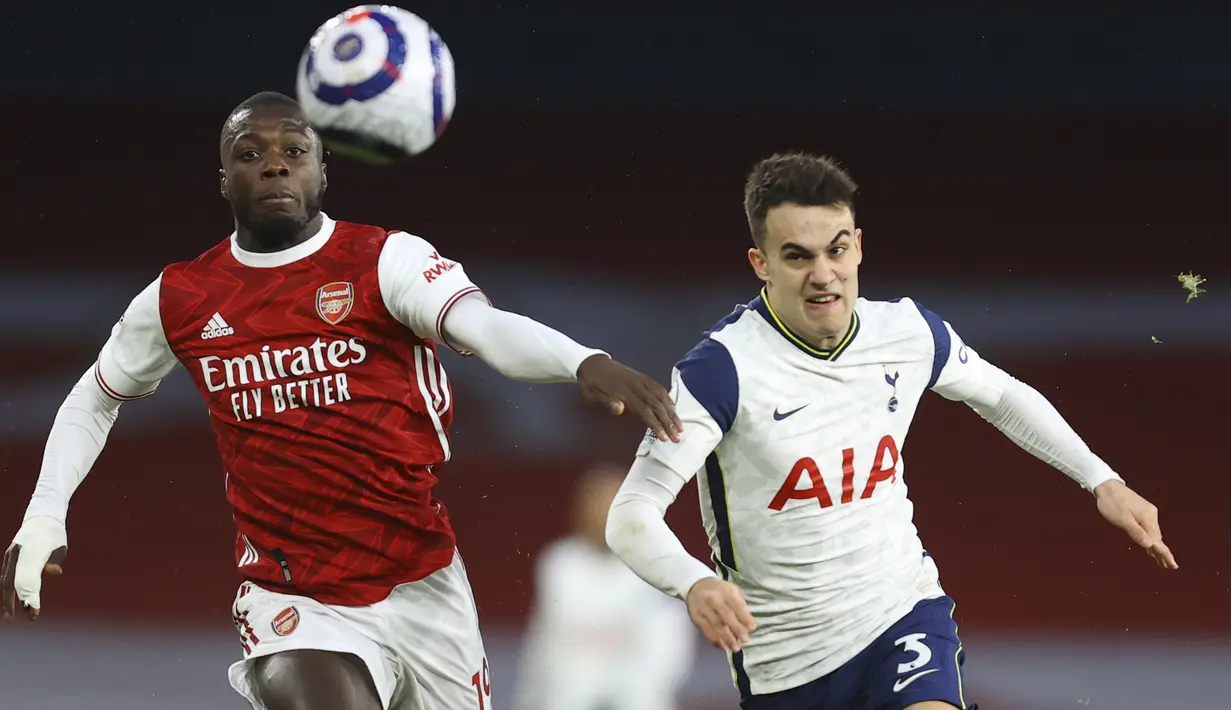Penyerang Arsenal, Nicolas Pepe berebut bola dengan bek Tottenham Hotspur, Sergio Reguilon dalam derby London Utara Liga Inggris di Emirates Stadium, Minggu (14/3/2021). Sempat tertinggal lebih dulu, Arsenal menang 2-1 di kandang sendiri melawan Tottenham Hotspur. (Julian Finney/Pool via AP)