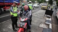 Anggota Polantas menilang pengendara motor yang melintas di jalur cepat di jalan Letjen Suprapto, Jakarta, Selasa (7/11). Sejauh ini, total ada 55.457 kendaraan yang telah ditilang oleh polisi. (Liputan6.com/Faizal Fanani)