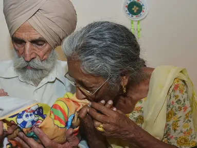 Pasangan Daljinder Kaur (kiri) bersama sang suami Mohinder Singh Gill saat menggendong bayi kesayangan mereka di Amritsar, India, Rabu (11/5).Nenek berusia 70 tahun ini berhasil melahirkan seorang bayi laki-laki bernama Armaan.( NARINDER NANU / AFP)