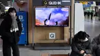 Seorang perempuan berjalan melewati layar televisi yang menayangkan siaran berita dengan rekaman file uji coba rudal Korea Utara, di sebuah stasiun kereta api di Seoul, Sabtu (31/12/20220). Korea Utara menutup akhir tahun 2022 dengan menembakkan tiga rudal balistik jarak pendek pada hari Sabtu, kata militer Korea Selatan. (Jung Yeon-je / AFP)