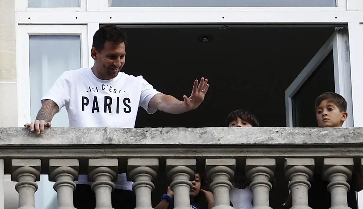 Pemain sepak bola Argentina Lionel Messi (kiri) melambai ke arah fans dari balkon hotel Royal Monceau di Paris pada Selasa (10/8/2021). Di Paris Saint-Germain (PSG), Messi akan dikontrak selama 2 tahun dan menerima gaji €35 juta per musim. (Sameer Al-DOUMY/AFP)