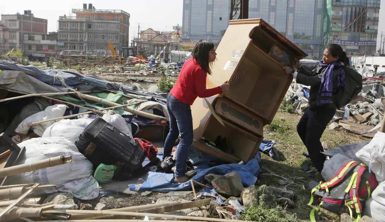 Warga membawa barang yang masih bisa terpakai di tempat pengungsian korban gempa bumi di Chuchepati, Kathmandu, Nepal, Selasa (14/3). Pemerintah Nepal terpaksa menggusur kamp ini karena sudah berdiri selama dua tahun. (AP Photo)