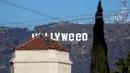 Tanda ikonik Hollywood yang diubah menjadi Hollyweed  di Hollywood Hills, Los Angeles, Minggu (1/1). Pelaku vandalisme , yang diduga seorang pria, menggunakan semacam terpal untuk mengubah huruf 'O' menjadi 'e'. (REUTERS/Kevork Djansezian)