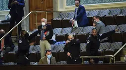 Anggota parlemen bersiap untuk mengevakuasi diri saat pengunjuk rasa mencoba masuk ke Gedung Capitol Hill di Washington DC, Amerika Serikat, Rabu (6/1/2021). Seorang wanita tewas ditembak dalam Gedung Capitol Hill. (AP Photo/J. Scott Applewhite)