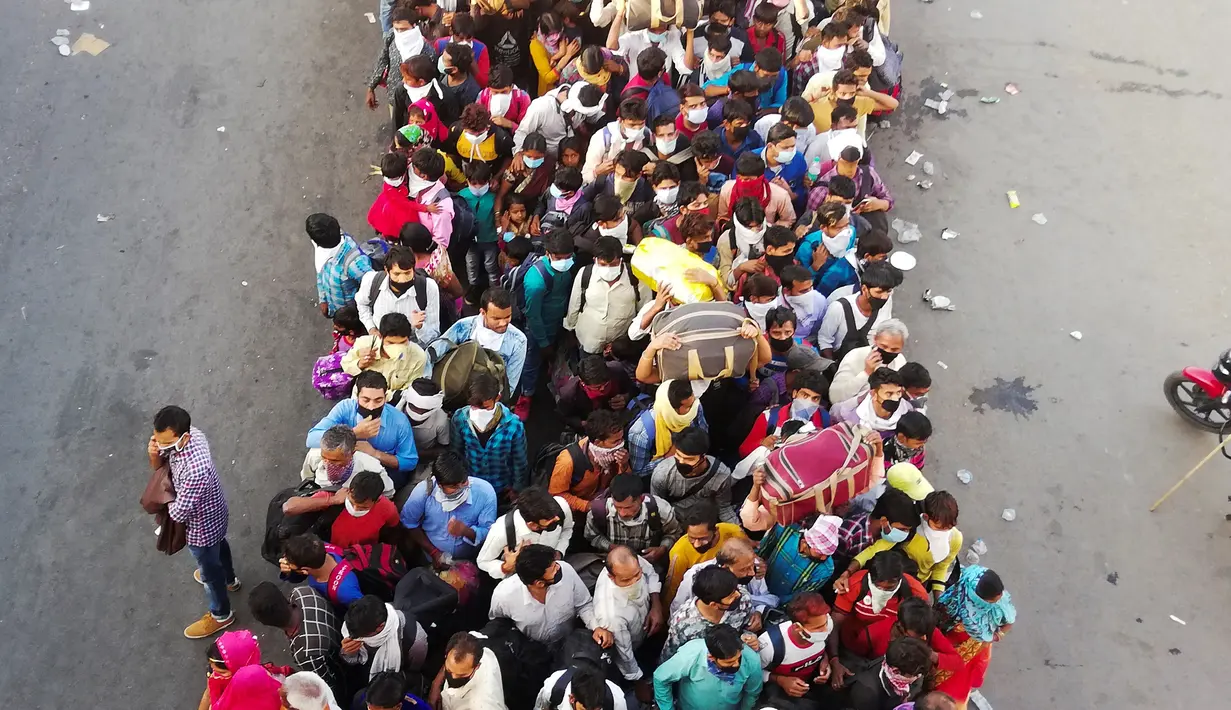 Pekerja migran dan anggota keluarga mereka menyerbu terminal bus Anand Vihar untuk pulang kampung selama pemberlakukan lockdown di New Delhi, Sabtu (28/3/2020). Ribuan orang meninggalkan New Delhi setelah pemerintah India memberlakukan lockdown untuk mencegah penyebaran COVID-19. (Bhuvan BAGGA/AFP)