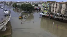 Orang-orang melintasi daerah banjir setelah hujan deras di Karachi, Pakistan, Minggu, (26/7/2020). Banjir melumpuhkan arus lalu lintas salah satu ruas jalan di Karachi. (AP Photo/Fareed Khan)