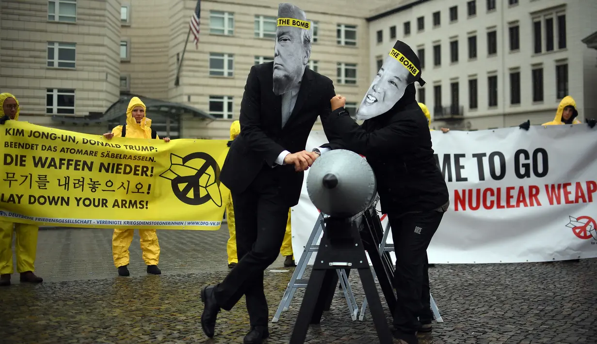 Dua aktivis memakai topeng Presiden AS, Donald Trump dan Pemimpin Korut, Kim Jon-un berpose di dekat rudal tiruan saat kampanye penghapusan Senjata Nuklir (ICAN) di Kedubes Korea Utara di Berlin, Jerman (13/9). (AFP Photo/dpa/Britta Pedersen/Germany Out)