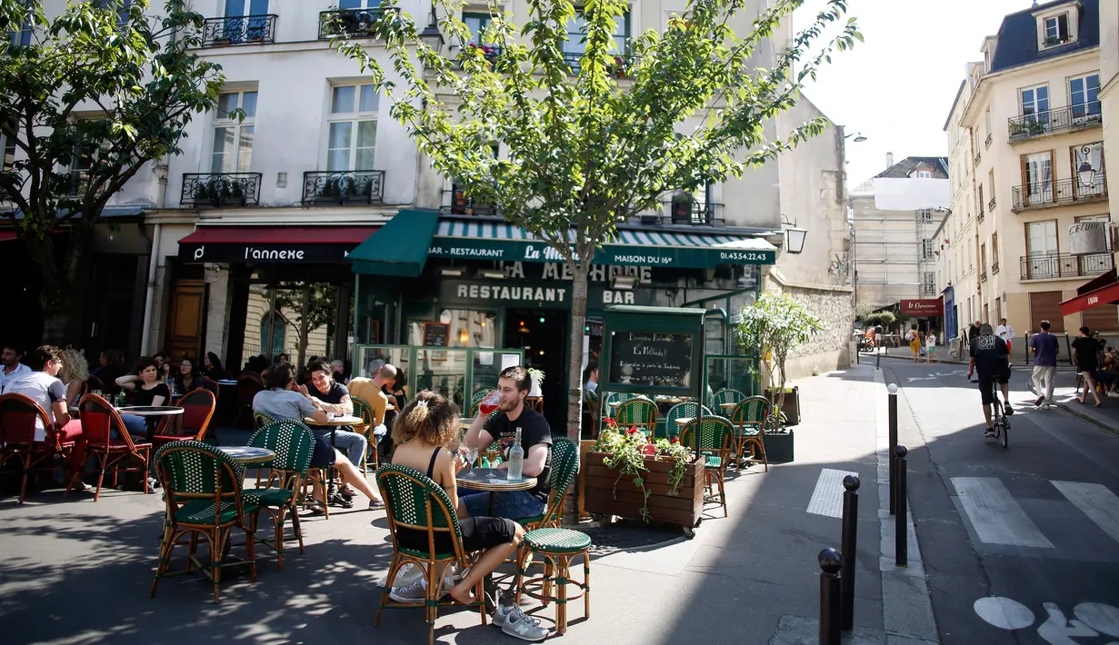 Orang-orang duduk di teras kafe di Paris, Selasa (2/6/2020). Warga Paris terkurung selama berbulan-bulan karena lockdown Corona namun, kini sebagian kafe dan restoran di kota itu dibuka kembali usai pelonggaran pembatasan. (AP Photo/Christophe Ena)
