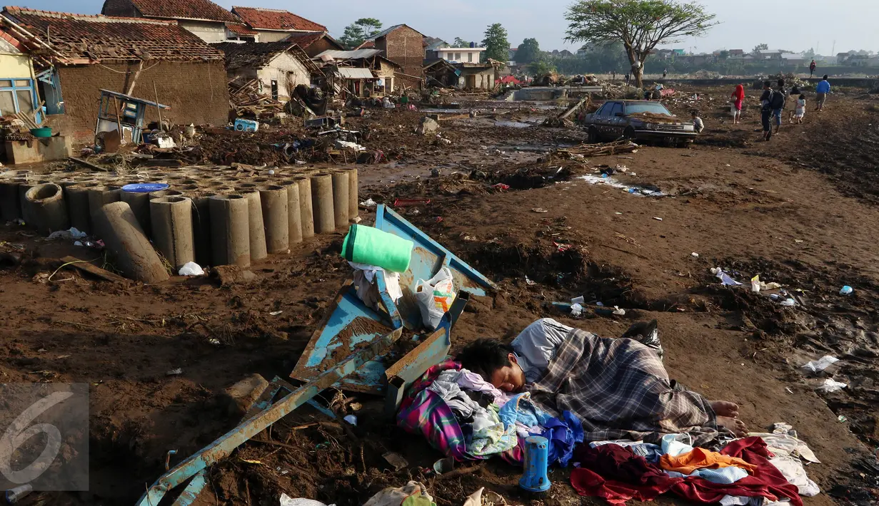 Warga tertidur ketika tengah melakukan evakusi barang setelah diterjang banjir bandang di Kampung Cimacan, Kecamatan Tarogong, Kabupaten Garut, Kamis (22/9). Data sementara Basarnas Jabar, 57 rumah hanyut dan 633 rumah terendam. (Liputan6.com/Johan Tallo)