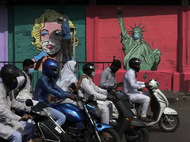 Seorang seniman melukis mural Marilyn Monroe, di samping salah satu Patung Liberty yang memakai masker untuk menyebarkan kesadaran akan pencegahan virus corona di Mumbai, India (26/3/2021). India telah melaporkan jumlah kasus virus corona tertinggi dalam empat bulan. (AP Photo/Rajanish Kakade)