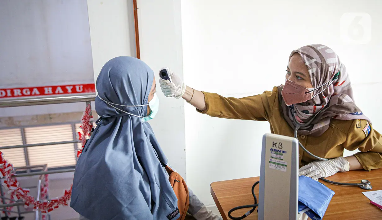 Petugas memeriksa suhu tubuh warga yang akan menjalani vaksinasi COVID-19 dari Pfizer di Puskesmas Lebak Bulus, Jakarta, Senin (23/8/2021). Sebanyak 1.560.780 dosis vaksin COVID-19 Pfizer tiba di Indonesia pada 19 Agustus 2021 melalui skema pembelian langsung. (Liputan6.com/Faizal Fanani)