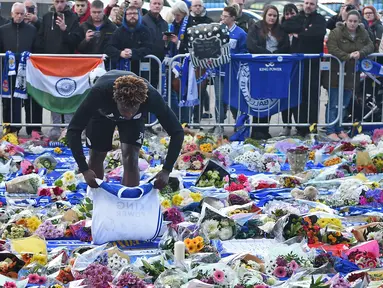 Pemain Leicester City, Darnell Johnson memberi penghormatan kepada korban kecelakaan helikopter yang menewaskan pemilik Leicester City Vichai Srivaddhanaprabha di luar Stadion King Power, Inggris, Senin (29/10). (Paul Ellis/AFP)