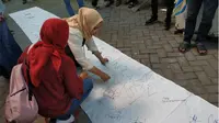 Wali murid membubuhkan tanda tangan tolak PPDB sistem zonasi di Kantor Dispendik Surabaya. Foto: Abidin suarasurabaya.net