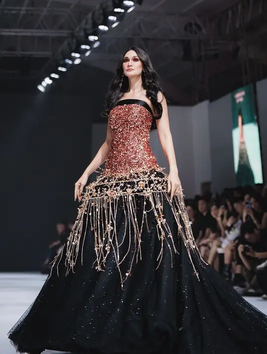 Luna Maya memancarkan pesona bak dewi dalam balutan strapless dress hitam berhiaskan beads emas berkilauan rancangan Christie Basil di JFW 2025.