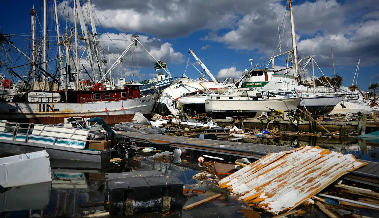 Perahu-perahu udang yang datang dari jauh ke bawah pantai duduk di atas sisa-sisa taman rumah mobil setelah diterjang Badai Ian di Pulau San Carlos, Pantai Fort Myers, Florida, Rabu (5/10/2022). Puing-puing berserakan di pantai, perahu terdampar dan beberapa bangunan tidak tersisa sama sekali. (AP Photo/Rebecca Blackwell)