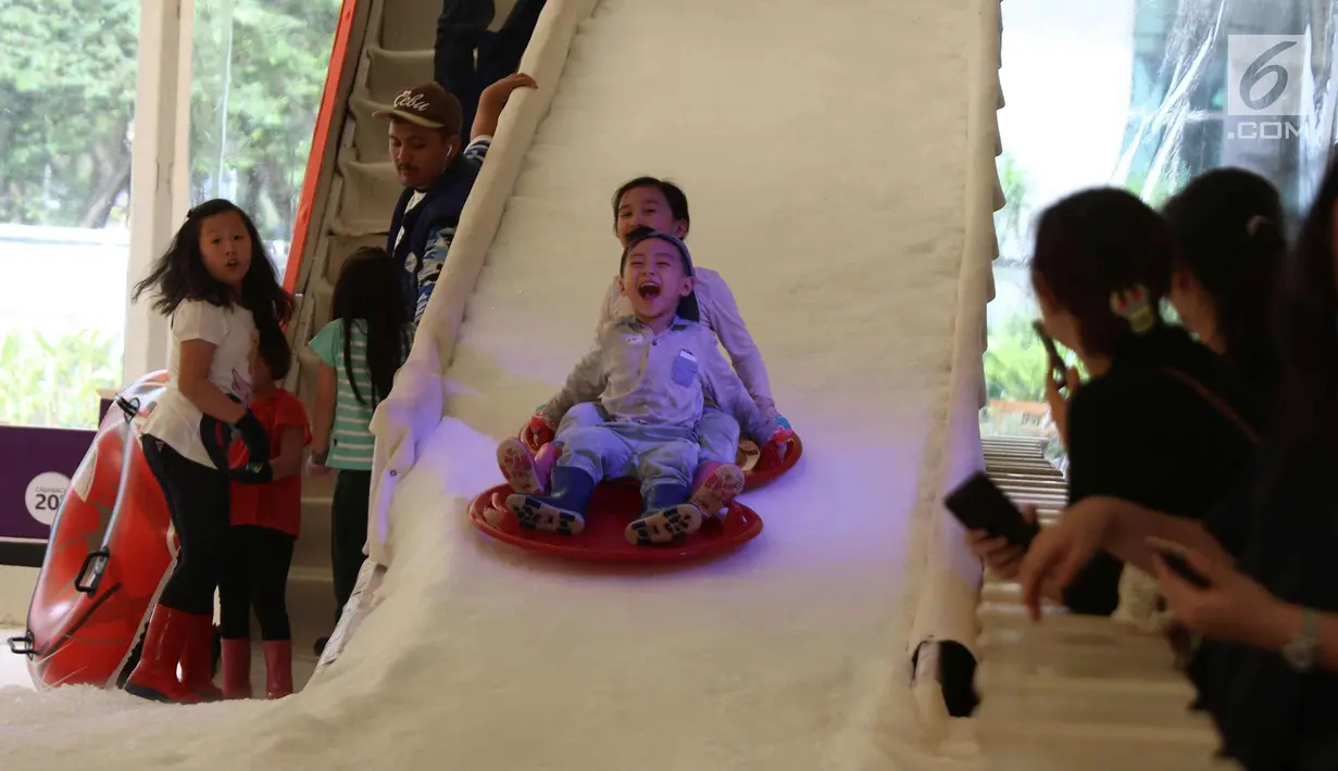 Ekspresi seorang anak berseluncur di perosotan es di Lippo Mal Puri, Jakarta, Jumat (22/12). Jelang Natal banyak pusat perbelanjaan mendekor bangunannya bernuansa natal untuk menarik daya tarik minat masyarakat. (Liputan6.com/Angga yuniar)