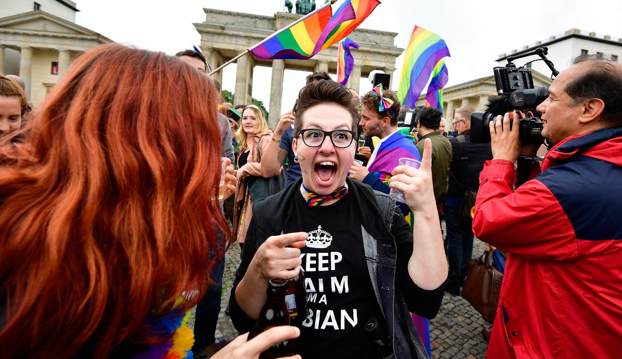 Seorang wanita merayakan keputusan legalisasi undang-undang pernikahan sesama jenis di depan Gerbang Brandenburg di Berlin (30/6). Dengan keputusan itu, maka UU pernikahan sejenis ini akan berlaku pada akhir tahun ini. (AFP Photo/Tobias Schwarz)