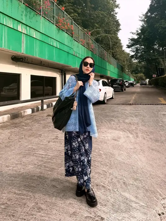Bunga Citra Lestari bergaya edgy padukan A-line outer lace dengan rok batik lilit dan loafers. Kerudung biru navy dan shoulder bag jadi sentuhan khas anak skena. [@itsmebcl]