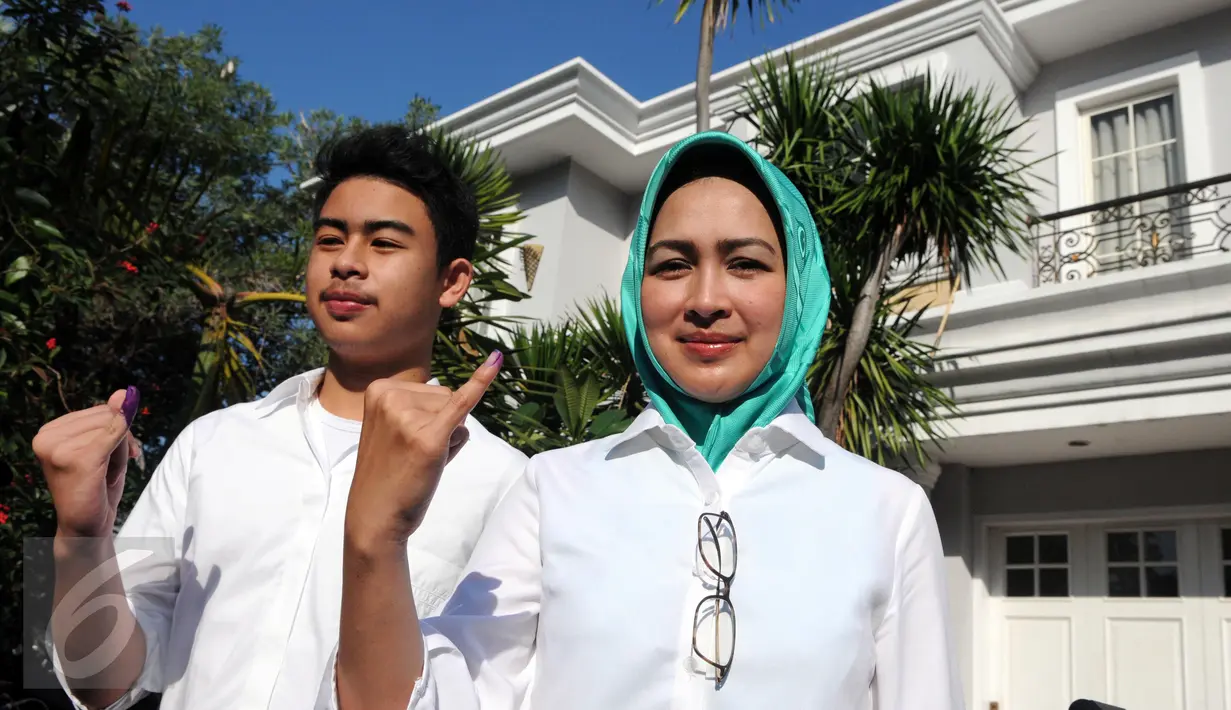 Calon Walikota Tangerang Selatan, Airin Rachmi Diany bersama putra pertama, TB Ghifari Wardana menunjukkan jarinya usai menggunakan hak pilih di TPS 17 Serpong Utara, Tangerang Selatan, Banten, Rabu (9/12). (Liputan6.com/Helmi Afandi)