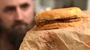 Casey Dean memeriksa burger McDonald's yang dibeli pada 1995 dan disimpan di gudang Australia selama bertahun-tahun, di Melbourne, 7 November 2019. Burger itu disimpan di dalam kotak terbuat dari kayu dan kardus dan ditutup menggunakan kunci di rumah Melbourne. (William WEST/AFP)