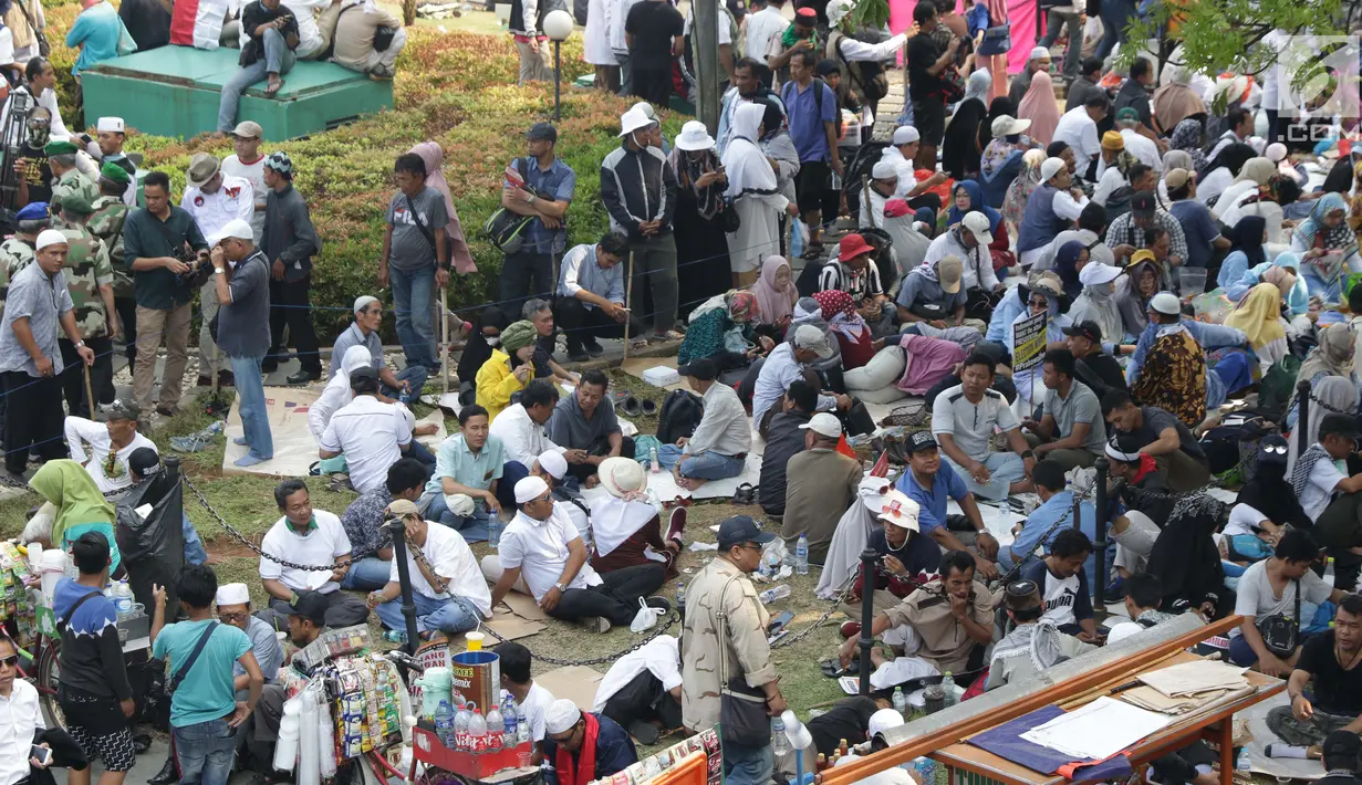 Massa aksi duduk-duduk beristirahat di taman belakang patung kuda Arjuna Wiwaha di Jalan Medan Merdeka Barat, Jakarta, Kamis (27/6/2019). Massa aksi berkumpul terkait pelaksanaan sidang putusan perselisihan hasil Pilpres 2019 di Gedung Mahkamah Konstitusi. (Liputan6.com/Helmi Fithriansyah)