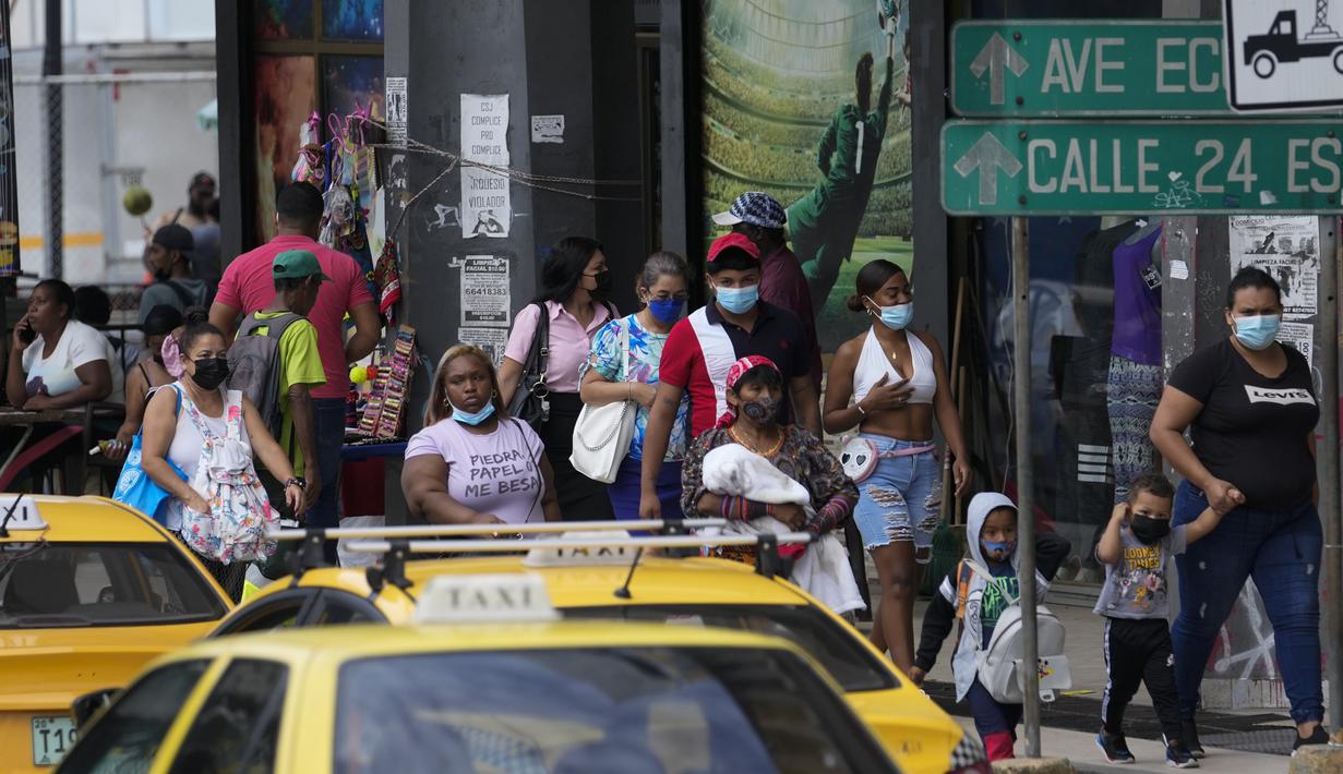 Orang-orang melintas di jalan pada hari pertama masker tidak lagi wajib di Panama City, Panama, Senin (11/7/2022). Masker tidak lagi diperlukan kecuali di rumah sakit dan transportasi umum. (AP Photo/Arnulfo Franco)