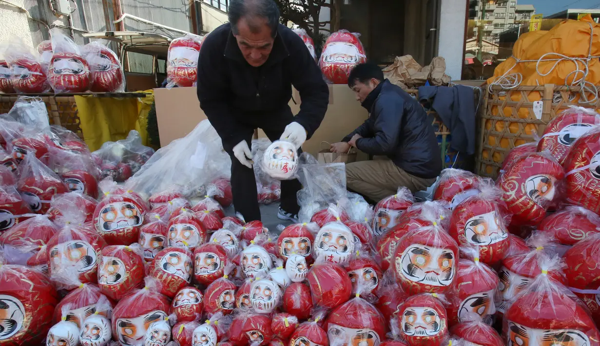 Seorang pedagang menata boneka merah Daruma yang dijajakan dalam pameran tahunan Oume Daruma di Tokyo, Jepang, 12 Januari 2018. Daruma atau boneka Dharma dijual dengan kedua belah mata yang belum digambar. (AP/Koji Sasahara)