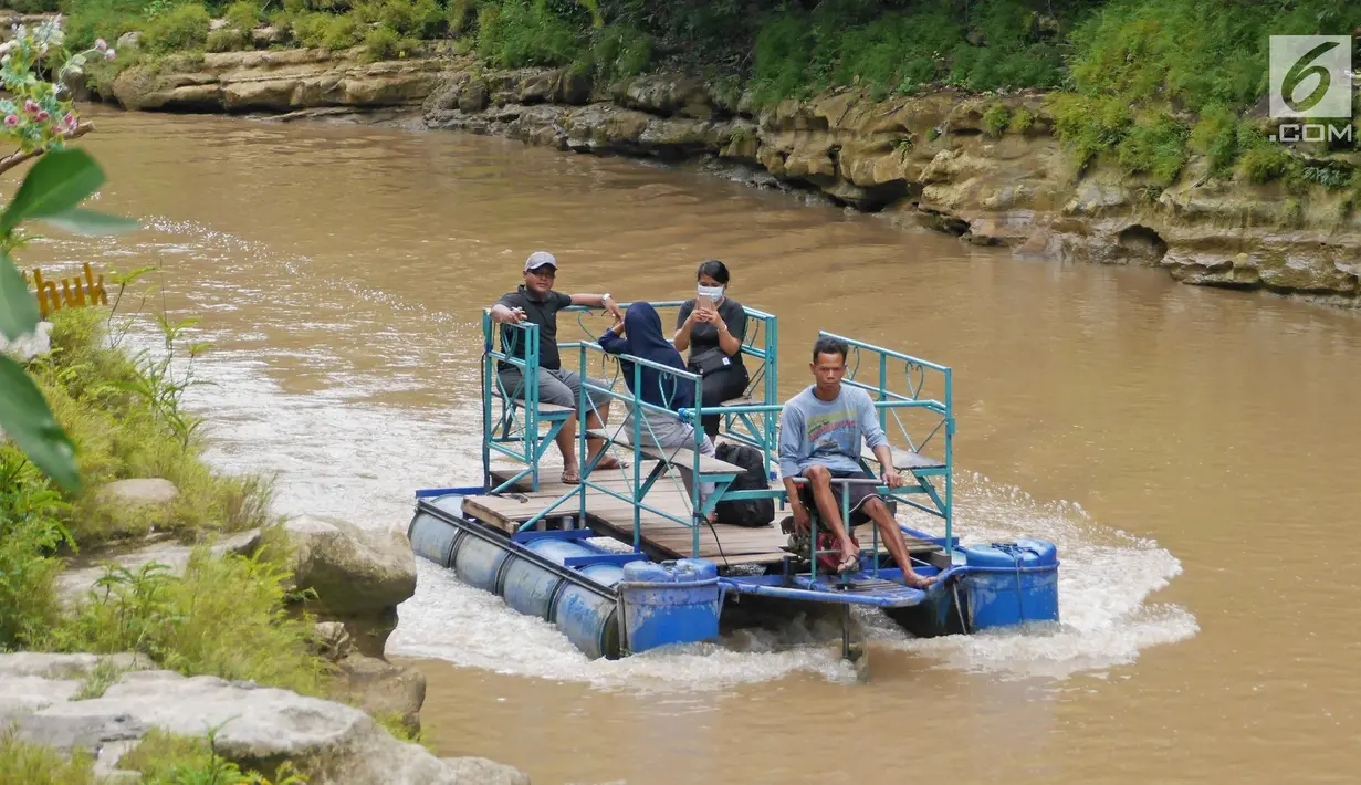 Sejumlah wisatawan menaiki rakit menuju Air Terjun Sri Gethuk, Kabupaten Gunungkidul, Yogyakarta, Sabtu (11/11). Wisatawan harus menempuh perjalanan melintasi Sungai Oya sepanjang 400 meter. (Liputan6.com/Herman Zakharia)
