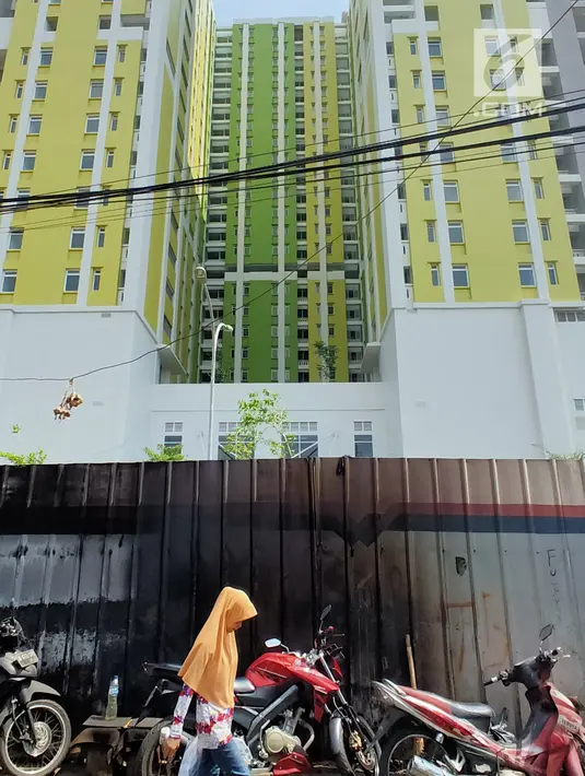 Warga berjalan dekat proyek Rusunawa Pasar Rumput yang hampir selesai pengerjaannya di Jakarta, Selasa (16/7/2019). Proyek yang dimulai sejak 2016 lalu tersebut memiliki 1.984 unit hunian serta 1.314 kios. (Liputan6.com/Immanuel Antonius)