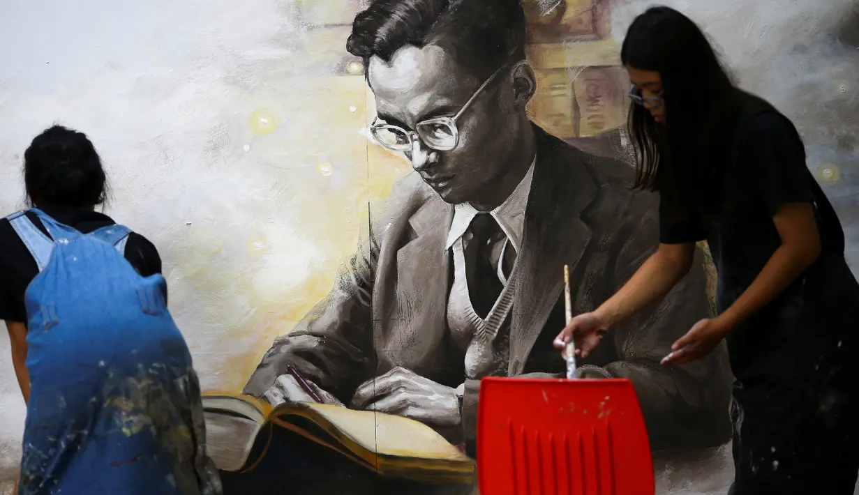 Dua mahasiswa seni di Thailand melukis gambar mendiang raja Raja Bhumibol Adulyadej di Universitas Silpakorn di Bangkok, Senin (17/10). Sejak wafatnya Raja Bhumibol, banyak warga memberikan macam-macam bentuk penghormatannya. (Reuters/Athit Perawongmetha)