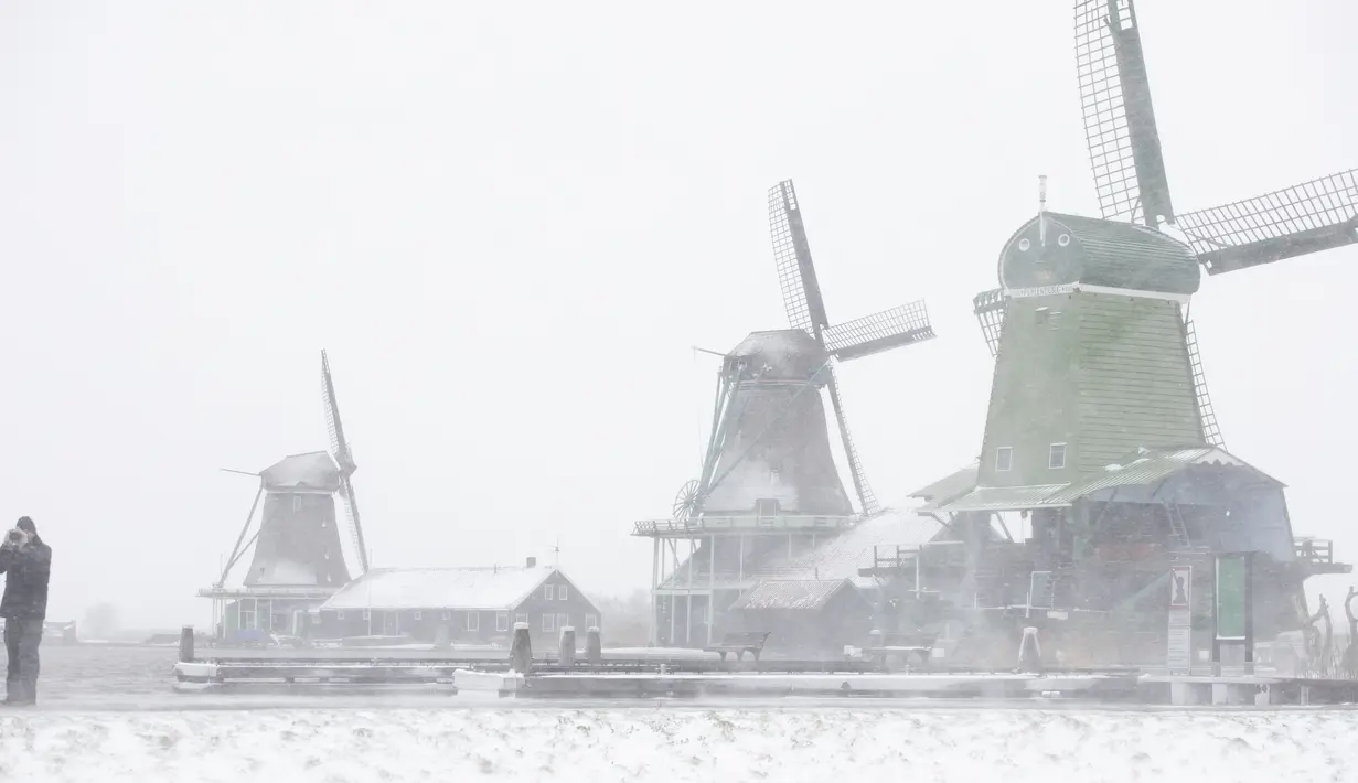 Seorang pria berfoto di Museum Zaan di Zaandam di dekat kota Amsterdam, Belanda saat salju dan angin kencang menerpa Belanda, Minggu (7/2/2021). (AP Photo/Peter Dejong)